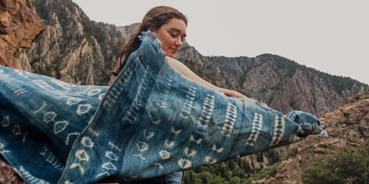 Woman holding a blue patterned blanket with mountains in the background